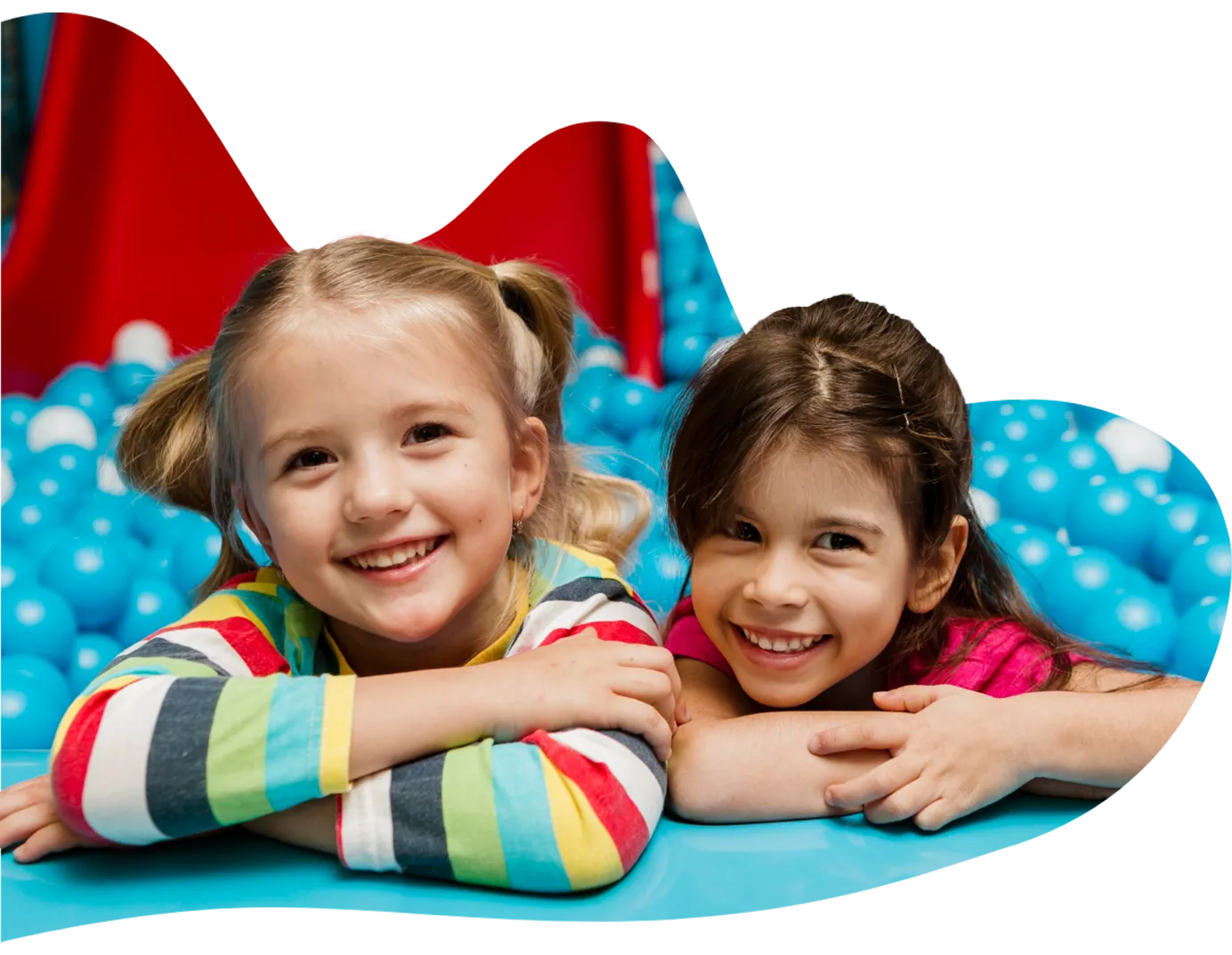 Playtropolis-kids-ball-pit-vaughanwebp - playtropolis Two smiling young girls leaning on the edge of a blue ball pit, looking at the camera in an indoor play area.