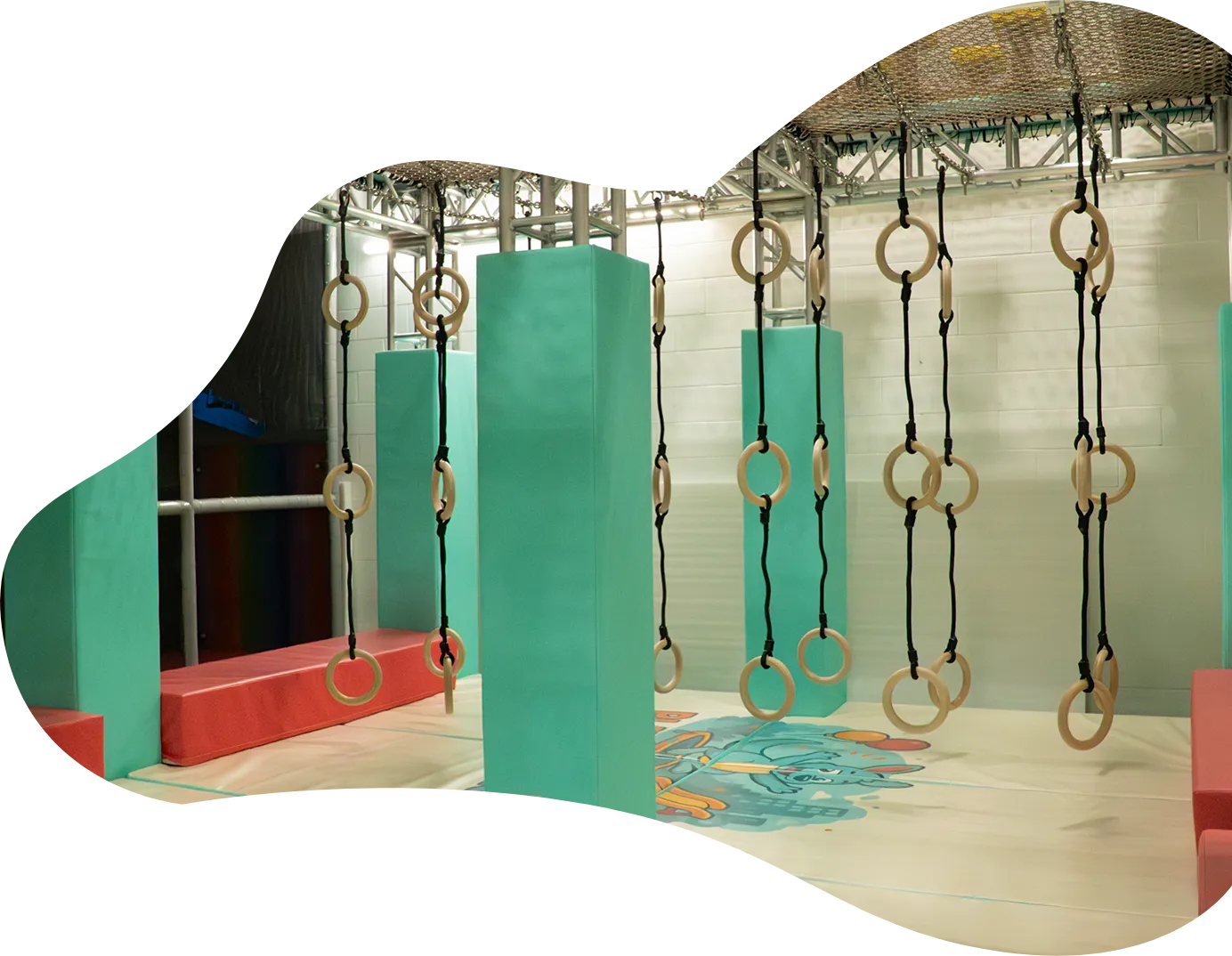Playtropolis-ninja-warrior-gymnastic-rings-woodbridgewebp - playtropolis Indoor children's obstacle course with hanging rings and padded turquoise pillars.