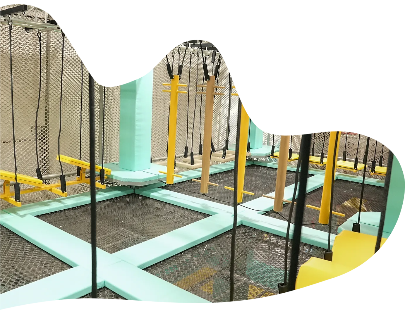 Playtropolis-ninja-warrior-obstacle-course-woodbridgewebp - playtropolis Indoor trampoline park obstacle course with turquoise padded beams, vertical posts, rope handles, and safety nets.